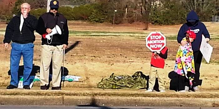 The child with the sign was observed almost stumbling into traffic Saturday