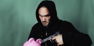 man pointing gun at piggy bank