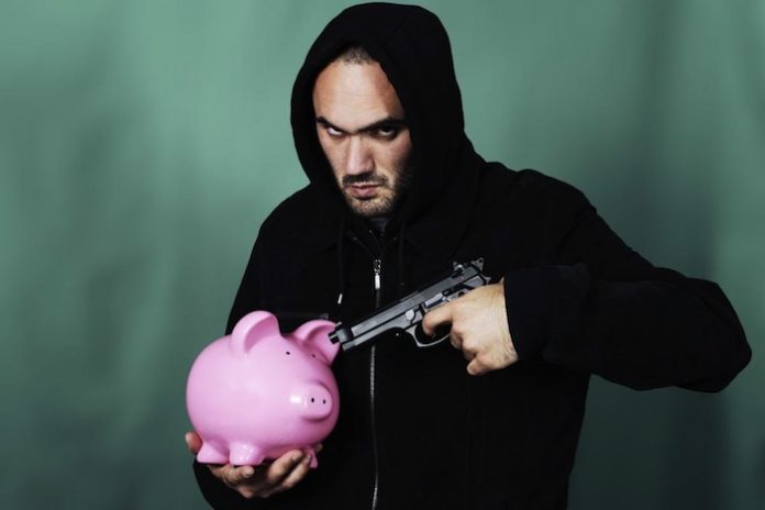 man pointing gun at piggy bank